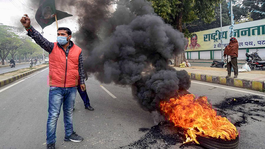 Rashtriya Janata Dal (RJD) workers burn a tyre and block a road during Bihar bandh protest over alleged erroneous results of Railway Recruitment Boards. Credit: PTI Photo