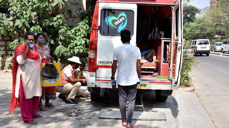 Police constable Kasappa Kallur helps change the punctured tyre of the ambulance near CID Junction on Palace Road on Tuesday. Credit: DH Photo/B K Janardhan