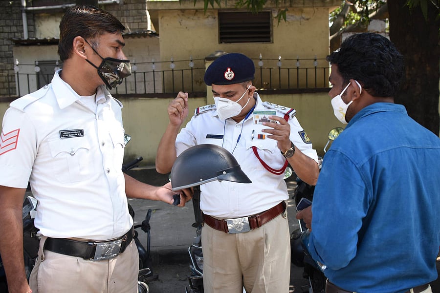 A constable educates a motorcyclist about the hazards of wearing a substandard helmet during an awareness drive in Chamarajpet, Bengaluru, on February 1, 2022. DH FILE PHOTO/PUSHKAR V