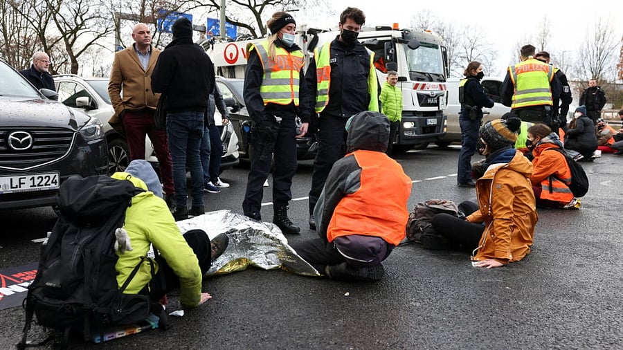 Police officers stand in front of "Letzte Generation" (Last Generation) activists who block the exit of a highway to protest against food waste and call for an agricultural change to reduce greenhouse gas emissions, in Berlin. Credit: Reuters photo