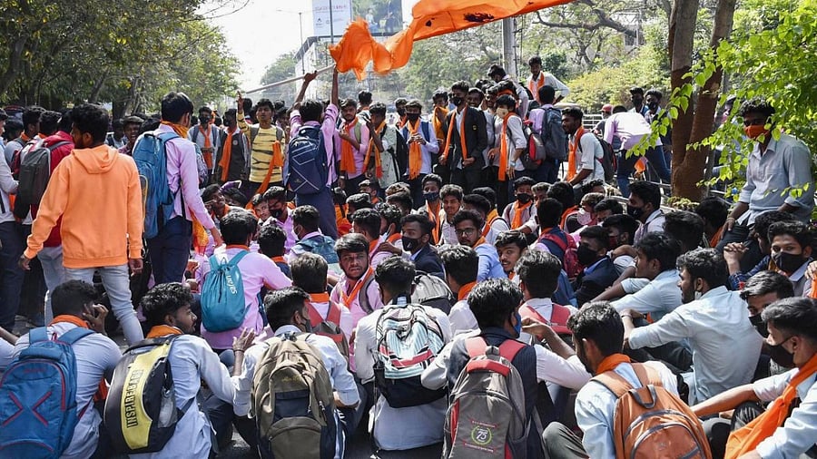 Students wearing saffron shawl block a road during protest over 'Hijab' controversy, in Shimoga. Credit: PTI photo