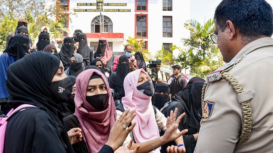 Muslim students talk to a police officer during a protest outside the Shivamogga District collector's office on Thursday. Credit: PTI Photo