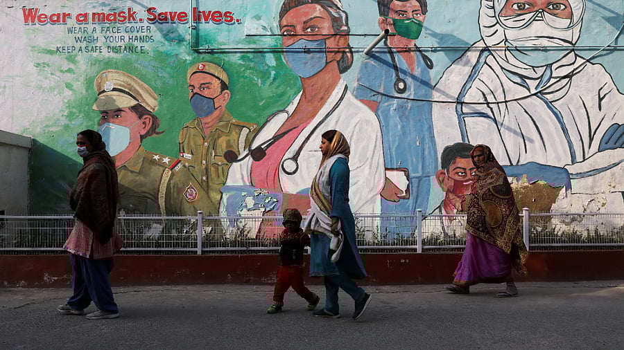 Women walk past a graffiti amidst the spread of the coronavirus disease (COVID-19) in New Delhi. Credit: Reuters Photo