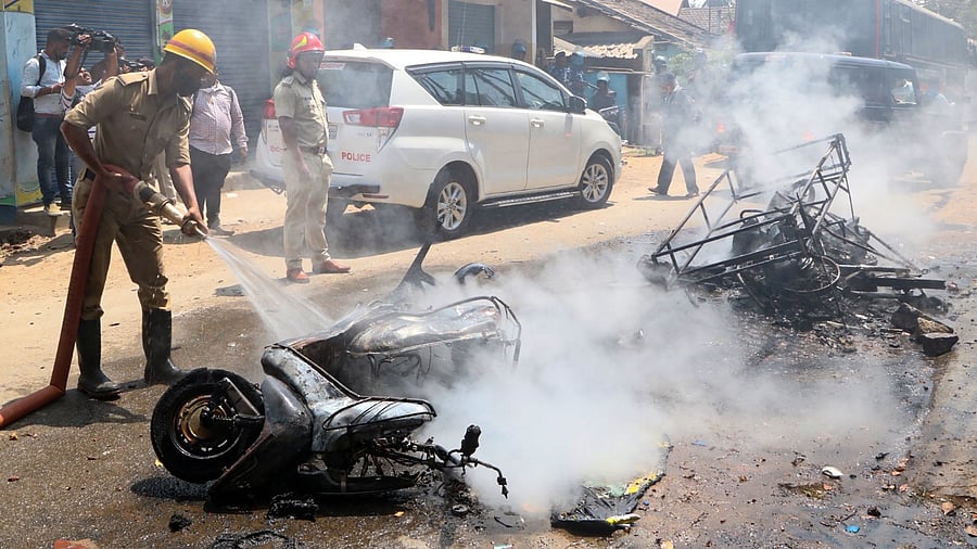 In this picture taken on February 21, 2022, a fireman douses fire from a burning vehicle set on fire by a mob after an unrest followed by the killing of a member of the Hindu nationalist group Bajrang Dal in Shivamogga in Karnataka. Credit: AFP Photo