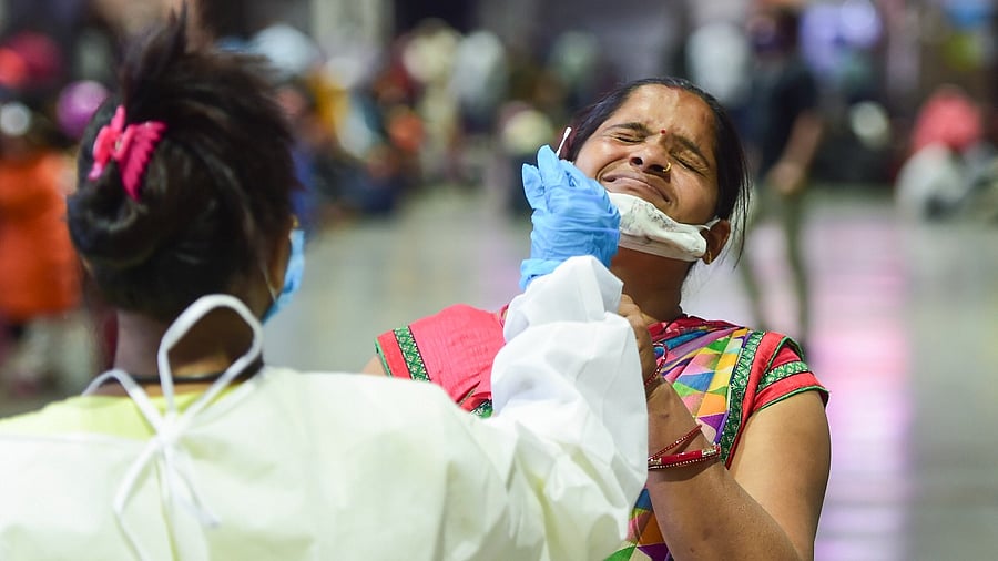 A BMC health worker collects swab sample of an outstation passenger for Covid-19 test, at Chhatrapati Shivaji Maharaj Terminus in Mumbai. Credit: PTI File Photo