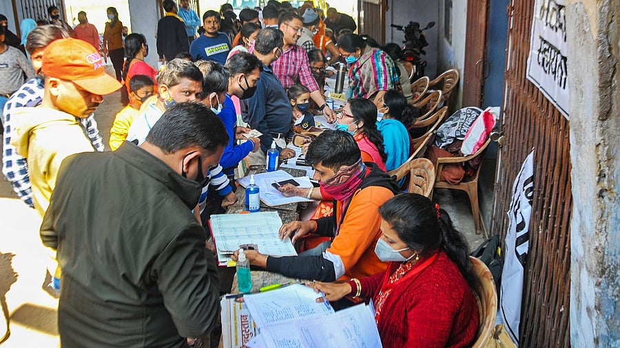 People check their names in the voters' list at a polling station, during the third phase of UP Assembly elections, in Kanpur, Sunday, February 20, 2022. Credit: PTI File Photo