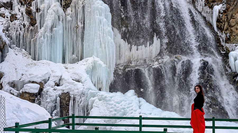 A woman gets clicked with a frozen waterfall in the backdrop. Credit: PTI Photo