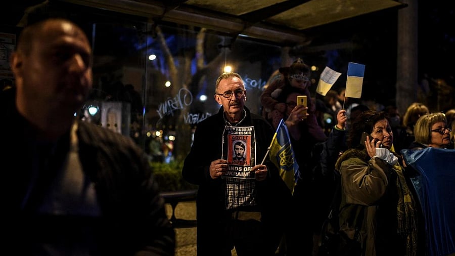 A demonstrator holds a sign depicting the Russian president as Adolf Hitler during a protest against Russia's military operation of Ukraine, in front of Belem Palace in Lisbon. Credit: AFP Photo