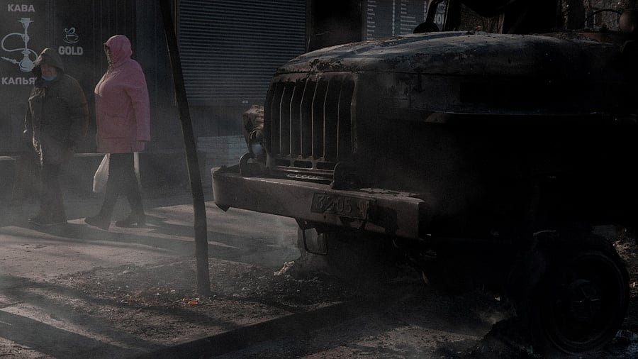 People walk past a burnt vehicle, as Russia's invasion of Ukraine continues, in Kyiv, Ukraine February 28, 2022. Credit: Jedrzej Nowicki/Agencja Wyborcza.pl via Reuters