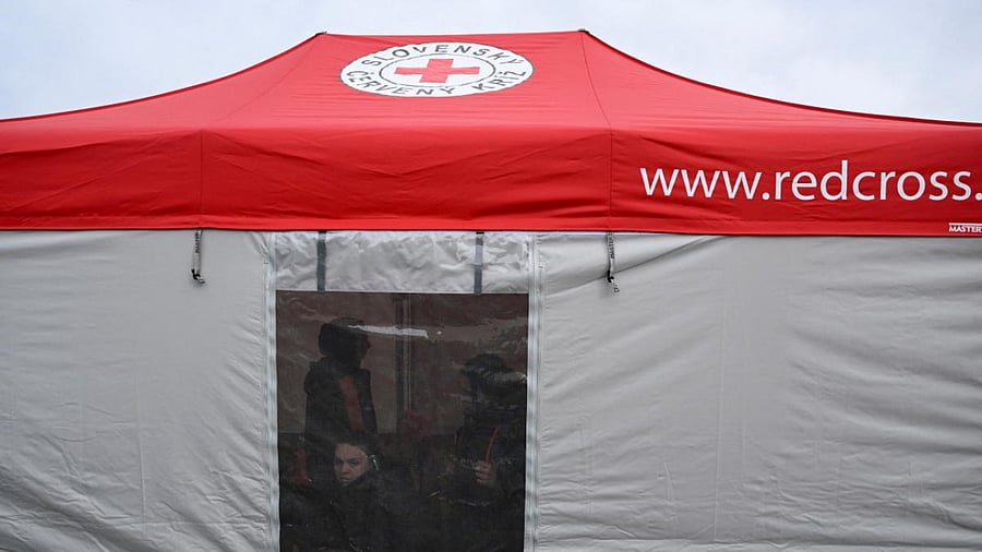 People stand and sit inside a Red Cross tent for people fleeing from Ukraine who arrive in Slovakia, after Russia launched a massive military operation against Ukraine, in Vysne Nemecke, Slovakia. Credit: Reuters Photo