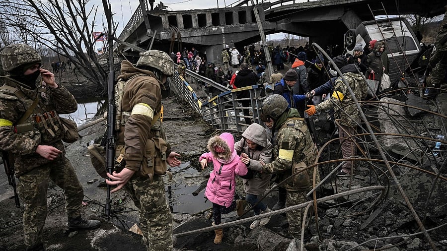 People cross a destroyed bridge as they evacuate the city of Irpin, northwest of Kyiv, during heavy shelling and bombing. Credit: AFP Photo
