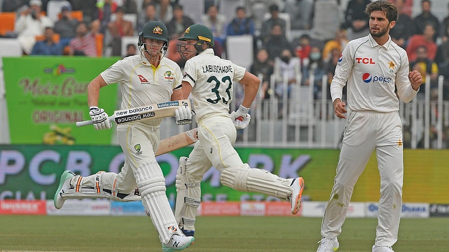 Australia's Stave Smith (L) and teammate Marnus Labuschagne (C) run between the wicket as Pakistan's Shaheen Shah Afridi watches during the third day of the first Test cricket match between Pakistan and Australia at the Rawalpindi Cricket Stadium in Rawalpindi on March 6, 2022. Credit: AFP Photo