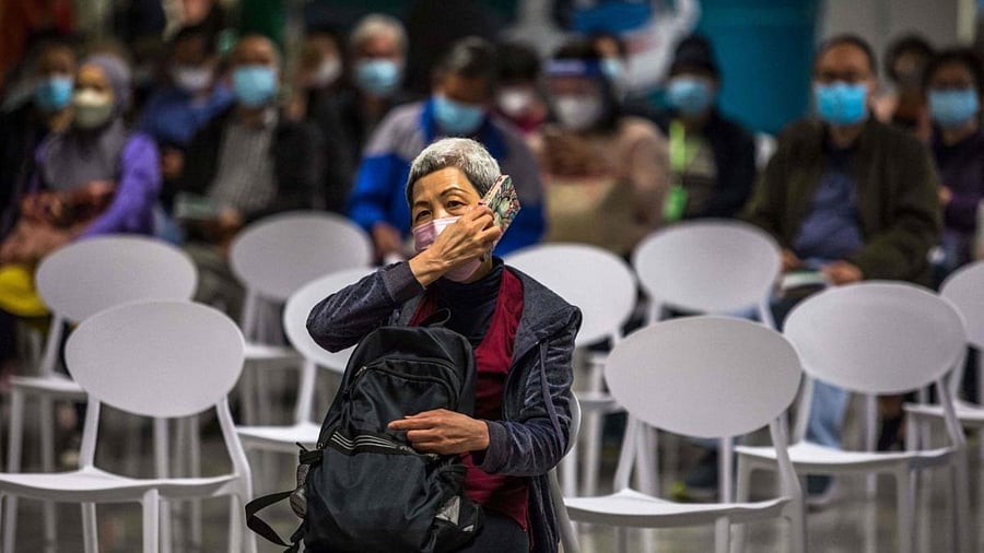 A woman uses her phone while sitting in a rest area after receiving the Sinovac Covid-19 coronavirus vaccine at a vaccination centre set up inside a train station in Hong Kong. Credit: AFP Photo