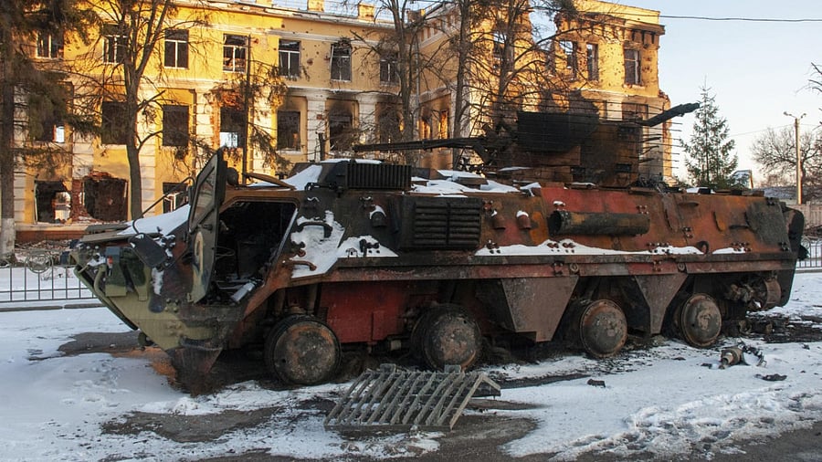 A destroyed armored personnel carrier stands in front of a damaged by shelling building in Kharkiv. Credit: AP/PTI Photo