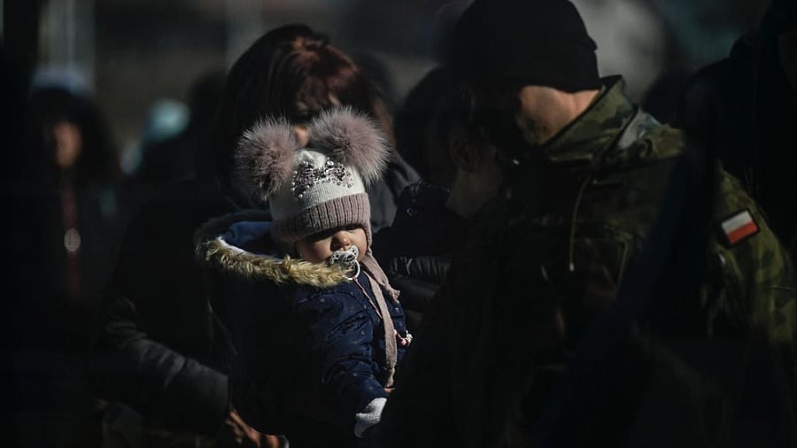 People wait for transportation after crossing the Ukrainian border into Poland, in Medyka, eastern Poland. Credit: AFP Photo
