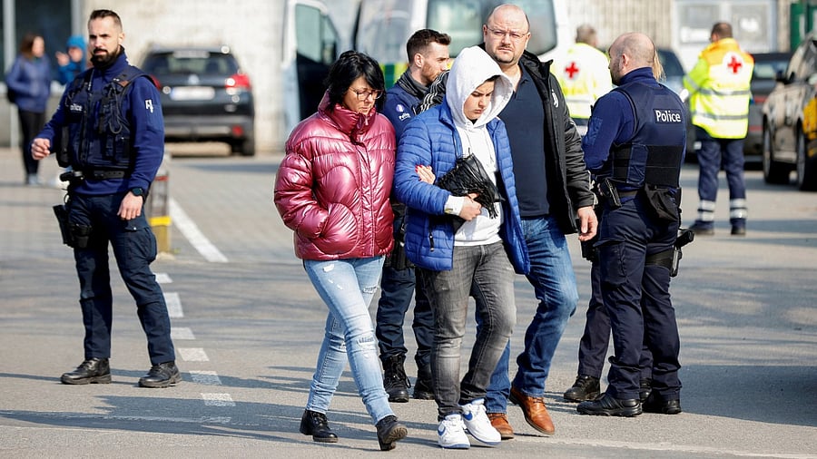 People walk as police officers keep guard near the site where a vehicle drove into a group of Belgian carnival performers who were preparing for a parade in the village of Strepy-Bracquegnies. Credit: Reuters photo
