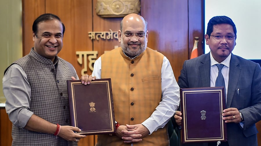 Assam Chief Minister Himanta Biswa Sarma(L) and Meghalaya Chief Minister Conrad K Sangma (R) sign an agreement to resolve the boundary dispute between their states, in the presence of Union Home Minister Amit Shah. Credit: PTI Photo
