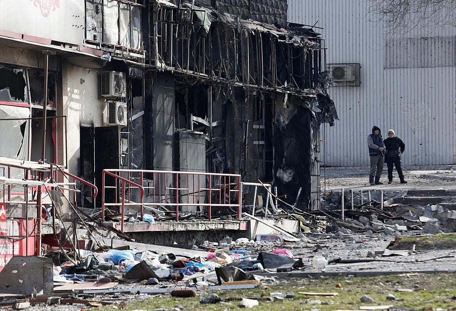 Local residents stand next to a damaged building in Mariupol. Credit; Reuters Photo