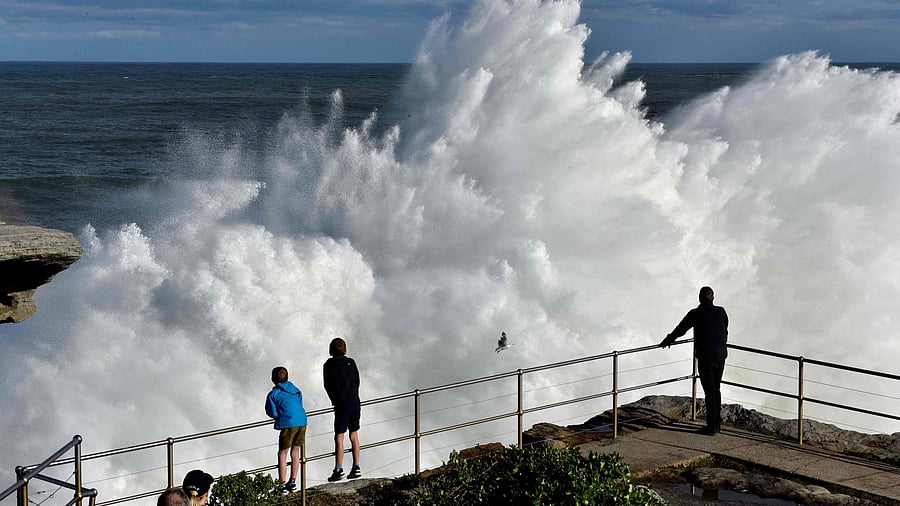 Residents watch a wave crashing into rocks at Bondi Beach in Sydney. Credit: AFP Photo