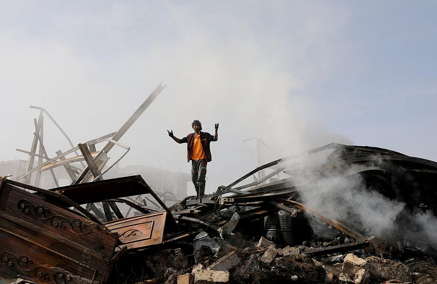 A worker reacts as he stands on the wreckage of a vehicle oil and tires store hit by Saudi-led air strikes. Credit: Reuters File Photo