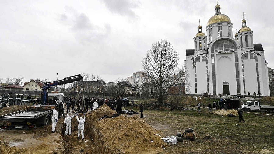 Ukrainian investigators exhume bodies from a mass grave in the gardens of the St Andrew church in the town of Bucha. Credit: AFP Photo