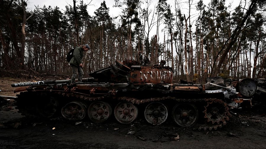 Man stands on the top of a destroyed Russian tank, amid Russia's Invasion of Ukraine near Buzova. Credit: Reuters Photo