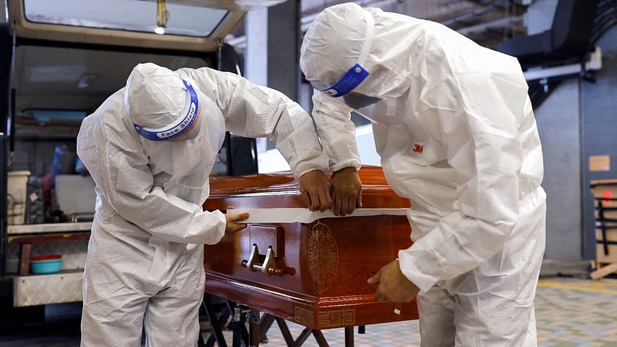 Medical workers handle the coffin of a Covid-19 victim. Credit: Reuters Photo