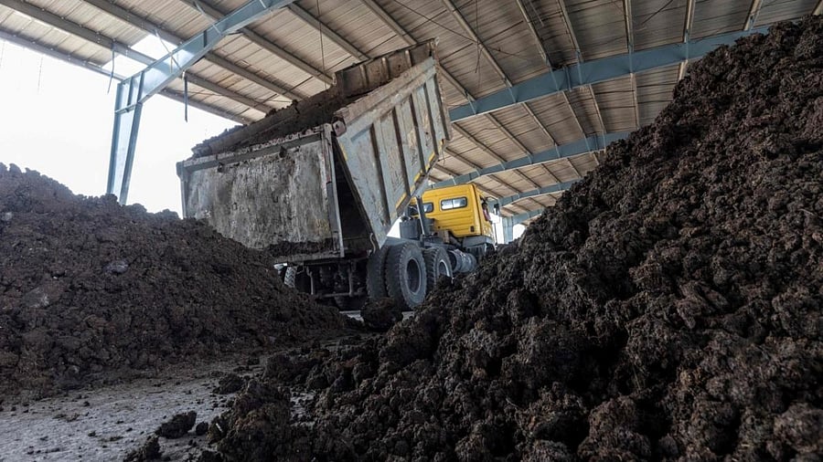 In this photograph taken on March 4, 2022, a truck unloads cow dung collected from farmers for biogas production at a storage area inside the bio-CNG (compressed natural gas) plant in Indore. Credit: AFP Photo