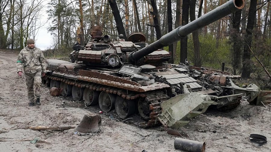 A Ukrainian soldier walks past a Russian tank after recent battles at the village of Moshchun close to Kyiv, Ukraine, April 19, 2022. Credit: AP Photo