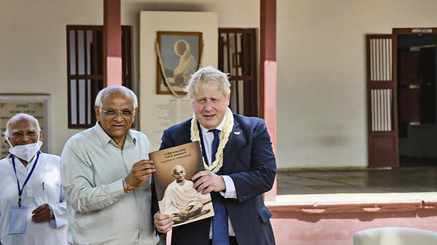 United Kingdom Prime Minister Boris Johnson being presented a memento by Gujarat Chief Minister Bhupendra Patel, during his visit to the Sabarmati Gandhi Ashram, in Ahmedabad. Credit: PTI Photo