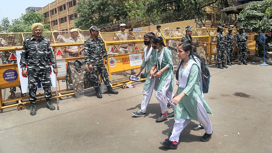 Security forces personnel stand guard as girls walk to school in the violence-hit Jahangirpuri area, in New Delhi. Credit: PTI Photo