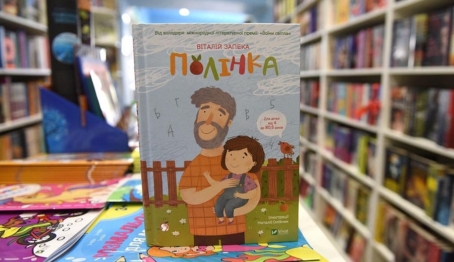 A copy of “Polinka”, a Ukrainian children’s book stands in a bookshop in the western city of Lviv on April 20, 2022, among hundreds of books evacuated from the bookshop’s publishing house in the embattled eastern Ukrainian city of Kharkiv. - Packed together in white parcels, the titles rescued from Kharkiv fill up what was once the children's reading room. They are just a fraction of those at the shop's publishing house in the eastern city under Russian fire. (Photo by Yuriy Dyachyshyn / AFP)