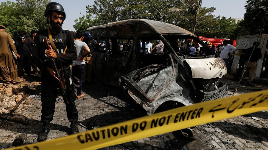 A police officer stands guard near a passenger van, cordoned after a blast at the entrance of the Confucius Institute University of Karachi. Credit: Reuters photo