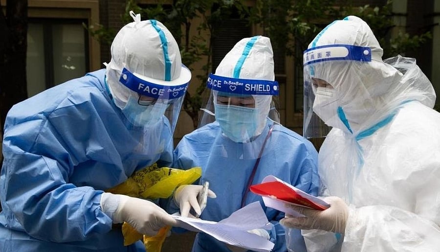 Tian Ge (L) and He Yanping (C) check residents' information with a community staff member in Beicai Town of east China's Shanghai, April 26, 2022. (Xinhua/Jin Liwang/IANS)