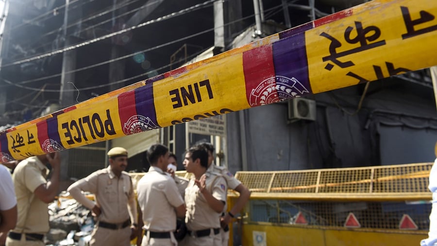 Police personnel stand guard at the site, after a massive fire at an office building near the Mundka Metro Station. Credit: PTI Photo