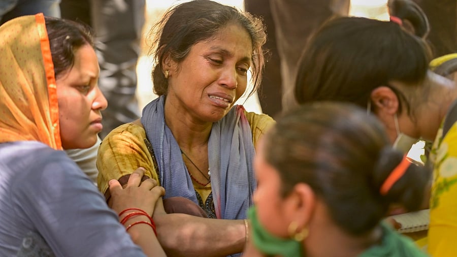 Family members of the missing people who are unsure about their whereabouts, react after a massive fire at an office building near the Mundka Metro Station. Credit: PTI Photo