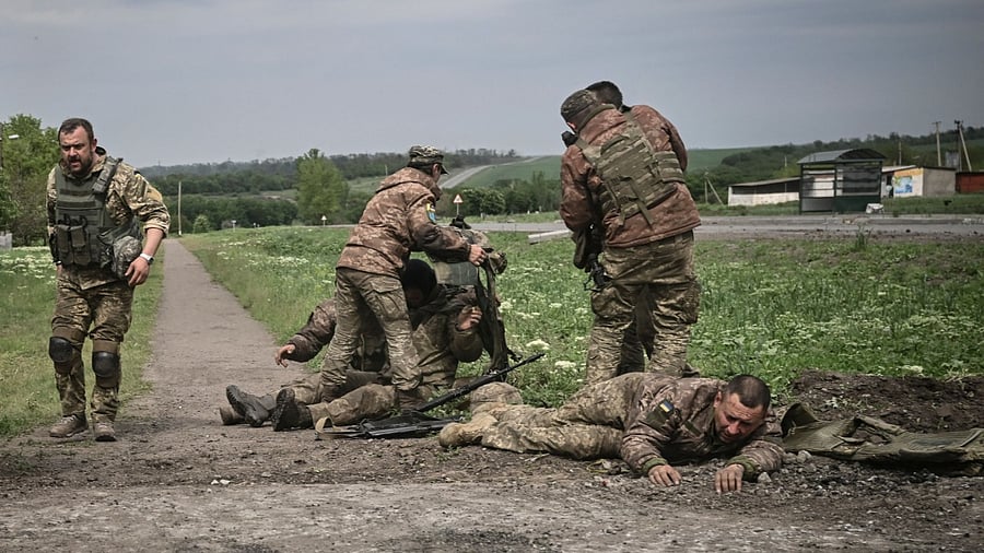 Ukrainian servicemen assist their comrades not far from the frontline in the eastern Ukrainian region of Donbas. Credit: AFP Photo