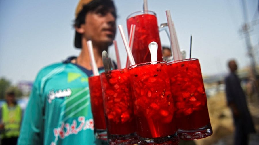 A vendor prepares to serve Rooh Afza watermelon beverages to customers along a roadside stall in Karachi. Credit: AFP Photo