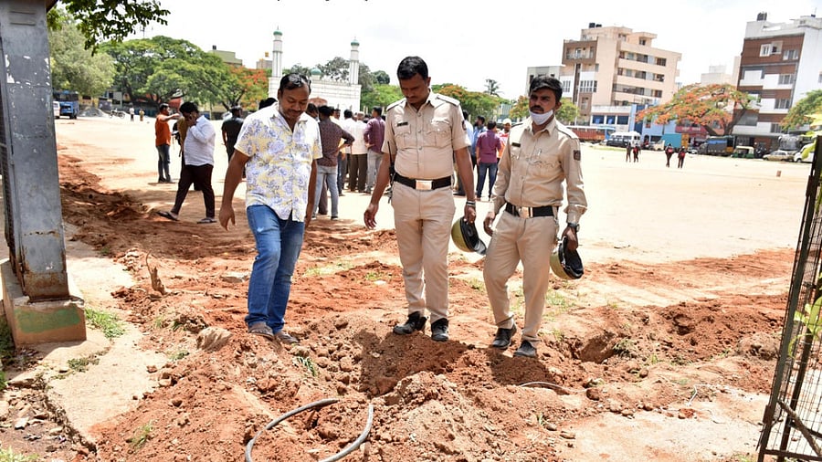 Policemen inspect the dug-up spot at the Chamarajpet Idgah Maidan in Bengaluru on Saturday. Credit: DH Photo
