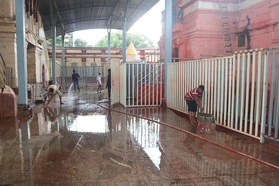 Workers at Renuka-Yallamma temple at Yallammanagudda in Savadatti taluk clean the premises after the flood waters recede. Sharp showers on Thursday evening left the 500-year-old temple inundated. Credit: DH Photo
