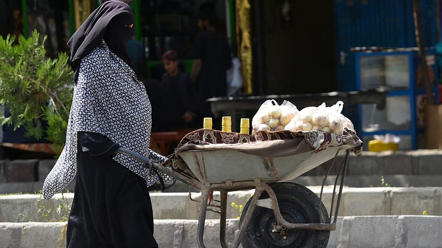A woman pushes a wheelbarrow loaded with onions along a street in Kabul. Credit: AFP Photo