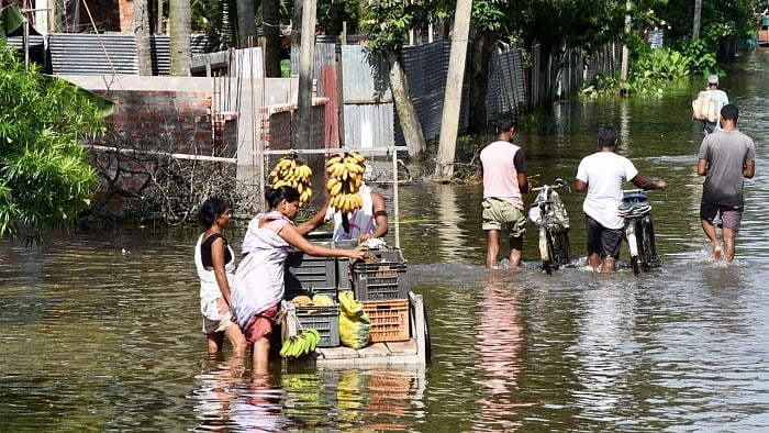 A vendor wades through a flooded street, in Kamrup district. Credit: PTI Photo
