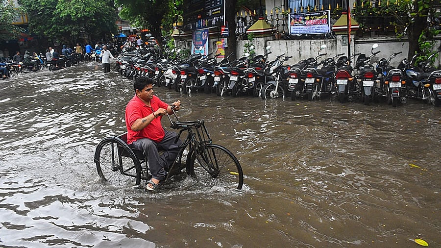 A man wades through a waterlogged street during monsoon rainfall, in Surat. Credit: PTI Photo