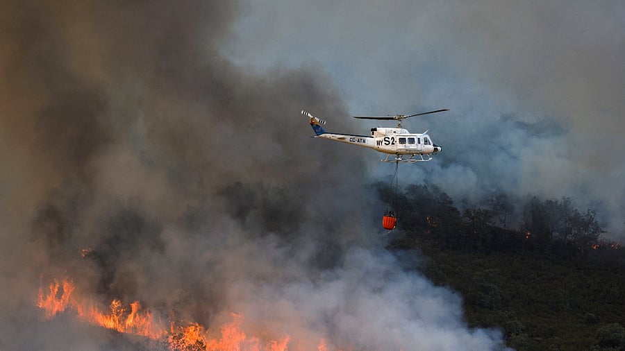 A helicopter works on containing a wildfire during the second heatwave of the year in the vicinity of Guadapero. Credit: Reuters photo