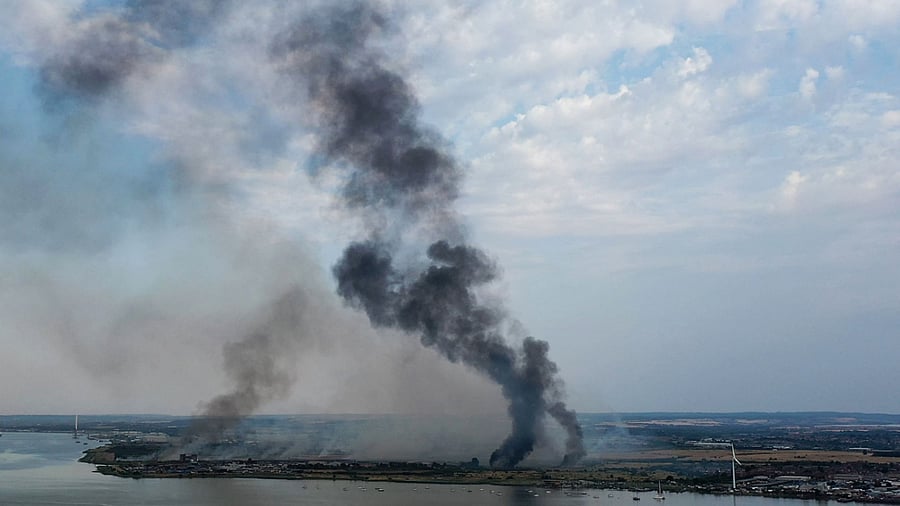 In this aerial view taken with a drone on July 19, 2022 smoke columns rise from Dartford, Kent, near London. Credit: AFP Photo