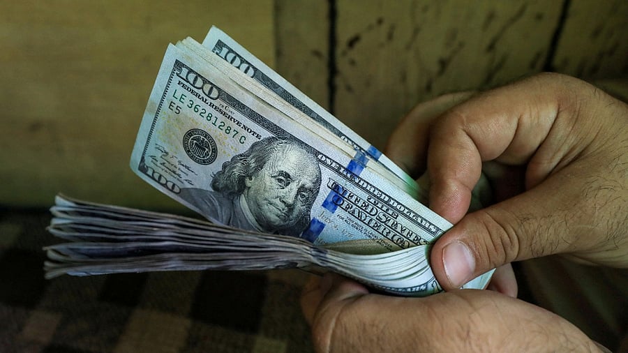 A trader counts U.S. dollar banknotes at a currency exchange booth. Credit: Reuters Photo