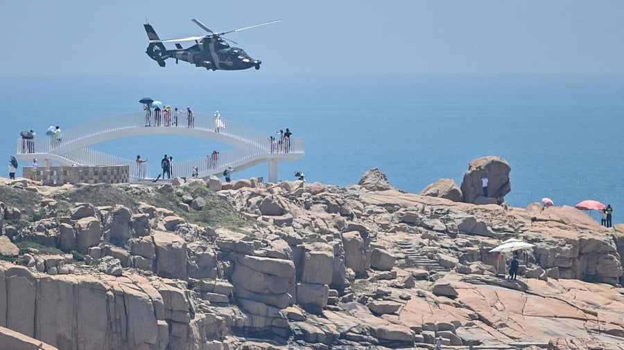Tourists look on as a Chinese military helicopter flies past Pingtan island, one of mainland China's closest point from Taiwan, in Fujian province on August 4, 2022, ahead of massive military drills off Taiwan following US House Speaker Nancy Pelosi's visit to the self-ruled island. Credit: AFP Photo
