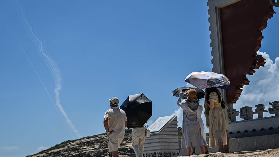 Smoke trails from projectiles launched by the Chinese military are seen in the sky as tourists look on from Pingtan Island, one of mainland China's closest point from Taiwan. Credit: AFP Photo 