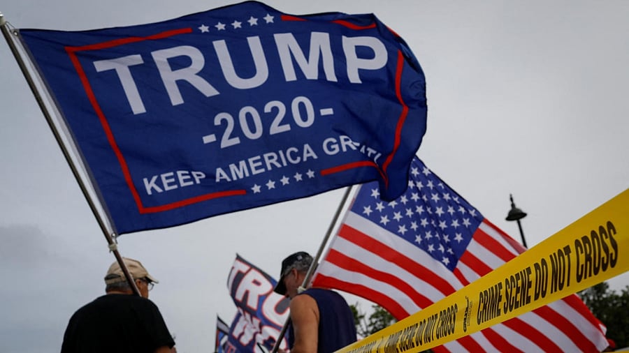 Supporters of former U.S. President Donald Trump wave flags as they gather outside his Mar-a-Lago home after Trump said that FBI agents raided it in Palm Beach, Florida. Credit: Reuters Photo
