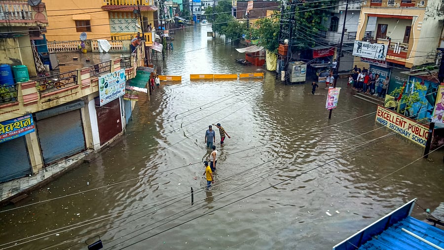 Locals wade through a waterlogged street following incessant monsoon rains, in Indore, Wednesday, Aug. 10. Credit: PTI Photo